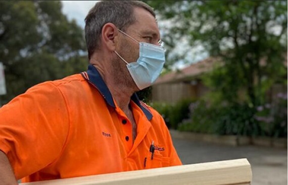 A man carrying a box wearing a respiratory mask