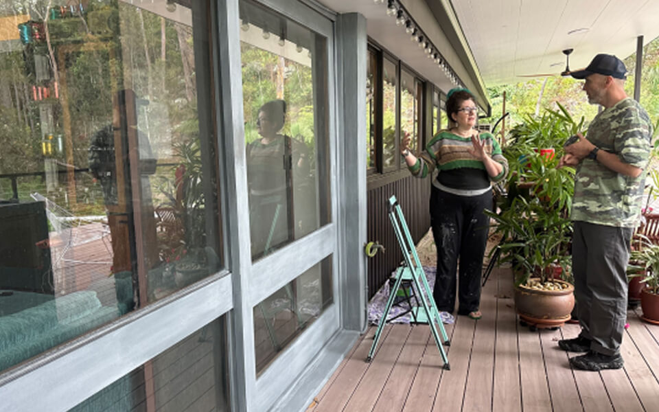 A man and woman standing in front of a painted door with windows A man and woman standing in front of a painted door with windows